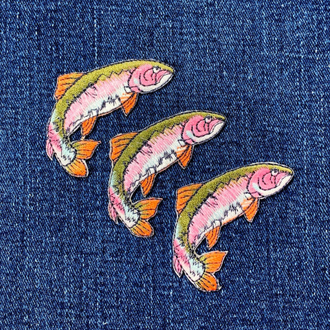 Three embroidered fish patches on a denim background