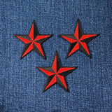 Three red and black star patches on blue denim fabric