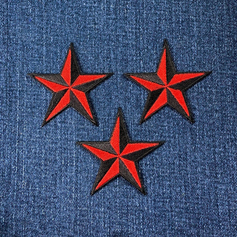 Three red and black star patches on blue denim fabric
