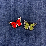 Two butterfly patches, one red and one green, on a denim fabric background.