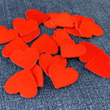 a pile of 20 red heart patches measuring 1 inch tall by 1 inch wide, displayed on a denim background