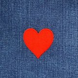 Red heart-shaped patch on blue denim fabric