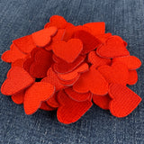 a pile of 50 mini red heart patches displayed on a blue denim background