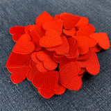 a pile of 50 mini red heart patches displayed on a blue denim background