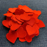 a pile of 50 mini red heart patches displayed on a blue denim background
