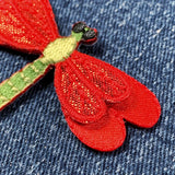 Red embroidered dragonfly patch on blue denim fabric