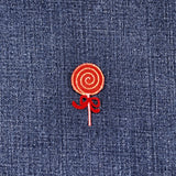 Red lollipop embroidered patch on blue denim fabric
