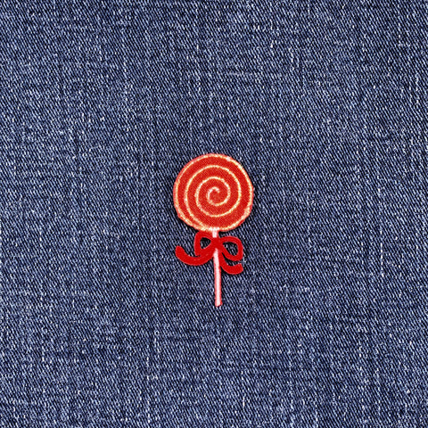Red lollipop embroidered patch on blue denim fabric