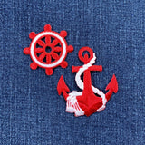 Red and white nautical wheel and anchor patches on a blue denim background