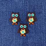 Three colorful owl patches on a denim background