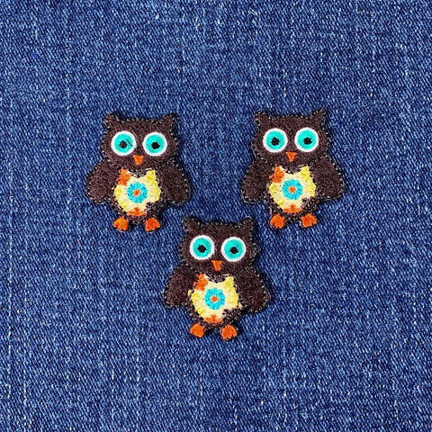 Three colorful owl patches on a denim background