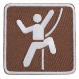An embroidered square patch featuring a white stylized figure climbing against a brown background, with a white border.