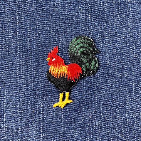 Colorful rooster patch on blue denim fabric
