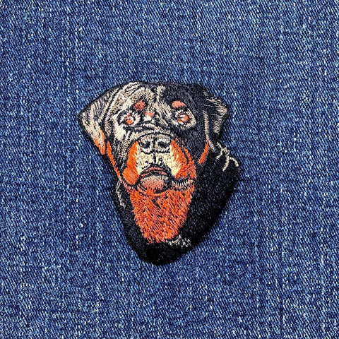 Embroidered patch of a Rottweiler dog's face on denim fabric