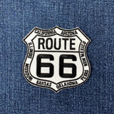 A shield-shaped patch with 'ROUTE 66' written in bold letters, surrounded by the names of US states in a circular pattern, and a badge number '66' in the center.