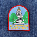 A patch featuring the California State Capitol Building with green trees, blue sky, and the text 'SACRAMENTO CALIFORNIA' on a denim background.