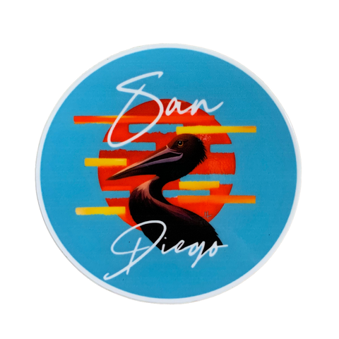 A circular sticker of a pelican is set against a striped orange and yellow sunset on a bright blue background. The words 'San Diego' are written above and below the bird.