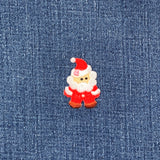 A embroidered Santa Claus applique patch with a red suit, white beard, and a brown base, designed for iron-on application on a denim background