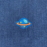 Planet-themed patch on a denim fabric background