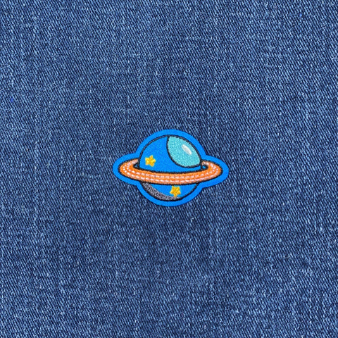 Planet-themed patch on a denim fabric background