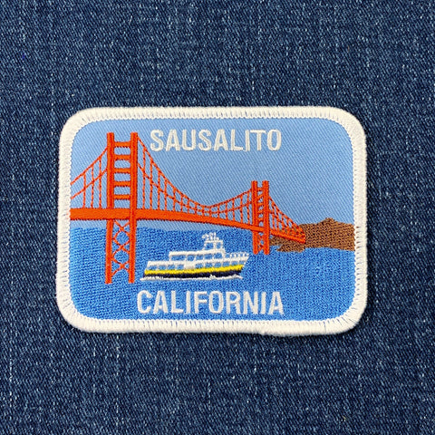 Embroidered patch of Sausalito, California with the golden gate bridge and ferry on denim fabric.