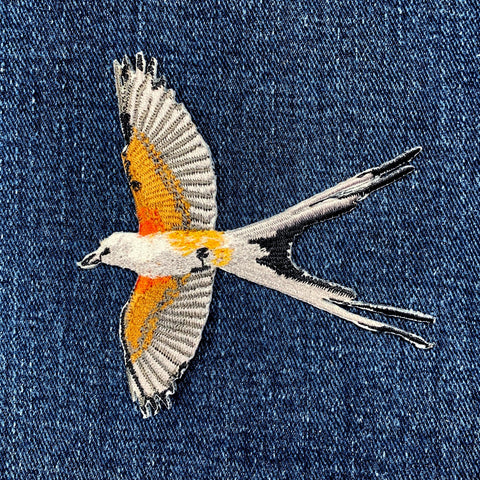 Embroidered bird patch on denim fabric