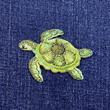 Embroidered green turtle patch on a blue denim background