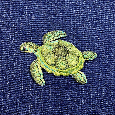 Embroidered green turtle patch on a blue denim background