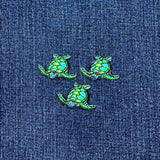Three green turtle patches on a blue denim background