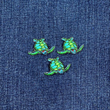 Three green sea turtle patches on a denim background