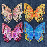 Four colorful butterfly patches with sequin details on a denim background