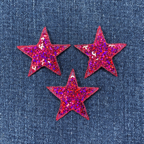 Three fuchsia glittery star-shaped patches on a denim background