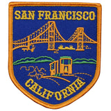 An orange-bordered, shield-shaped embroidered patch on blue denim shows the Golden Gate Bridge, a cable car, and hills.