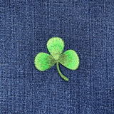 Green embroidered shamrock patch on blue denim fabric
