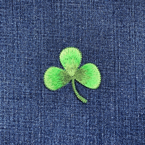 Green embroidered shamrock patch on blue denim fabric