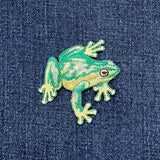 Green frog patch on a denim background