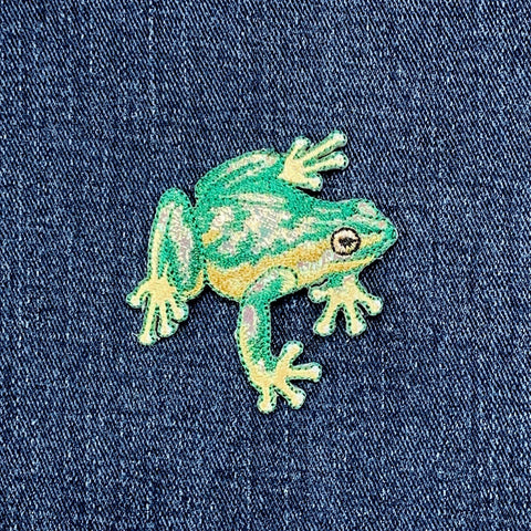 Green frog patch on a denim background