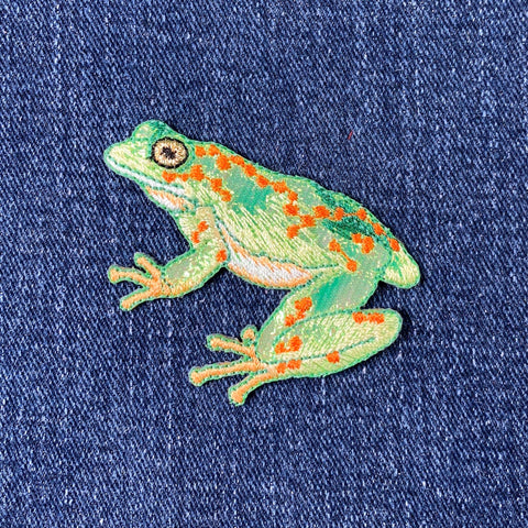 Embroidered frog patch on denim fabric