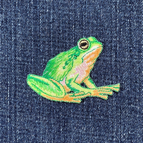 Embroidered green frog patch on denim fabric