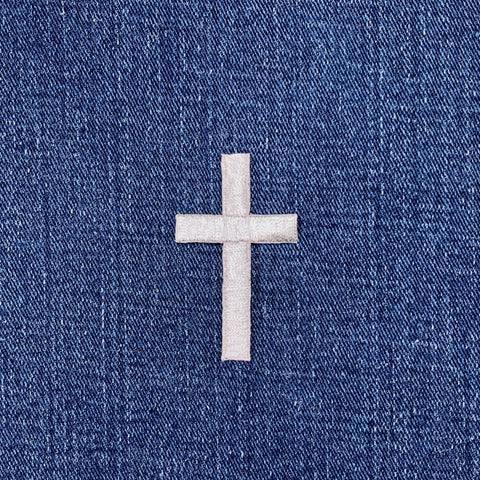Silver cross patch on blue denim fabric