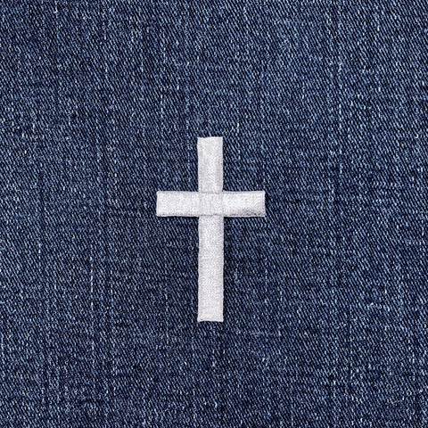 Silver cross patch on a blue denim background