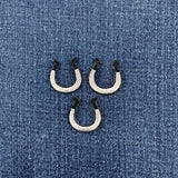 three silver and black horseshoe patches on a denim background