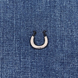 silver and black horseshoe patch on a denim background