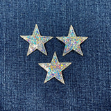 Three star-shaped sequin patches on a denim background