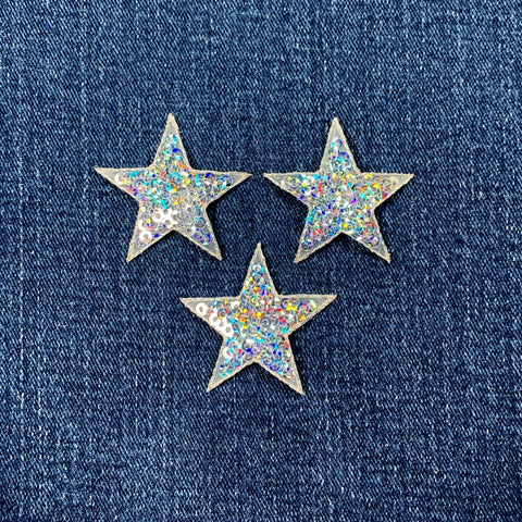 Three star-shaped sequin patches on a denim background