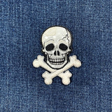 a shimmery silver skull patch on a denim background