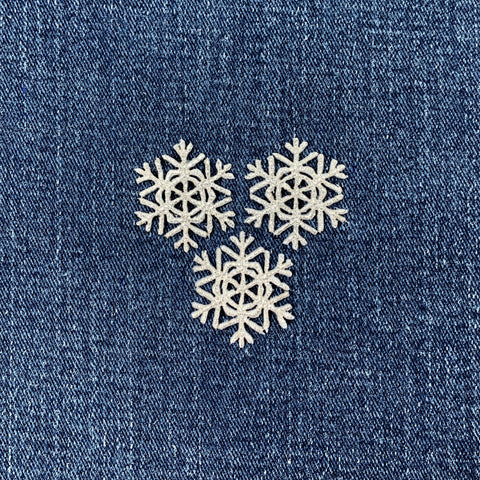 Three snowflake patches on a denim background