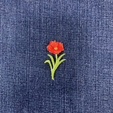 Embroidered red flower patch on blue denim fabric