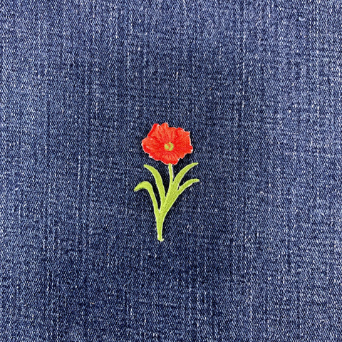Embroidered red flower patch on blue denim fabric