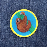 a round sloth patch displayed on a denim background